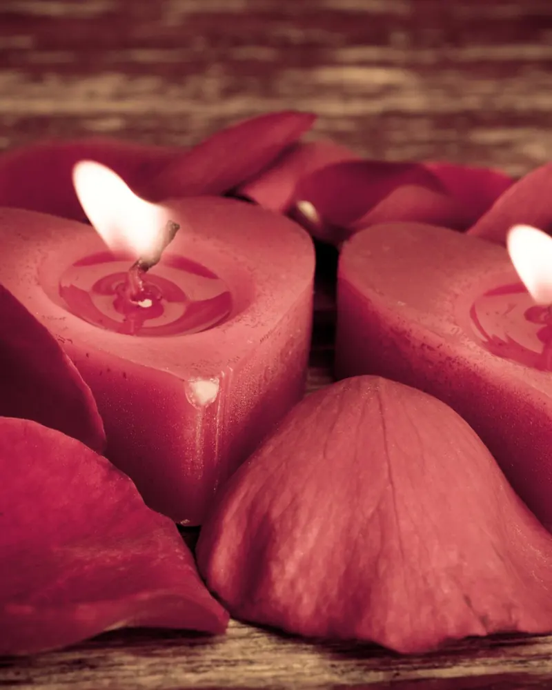 Heart-shaped candles among rose petals